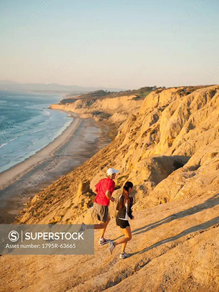 USA, California, San Diego, Man and woman jogging along sea coast