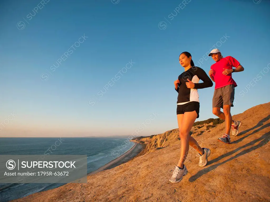 USA, California, San Diego, Man and woman jogging along sea coast