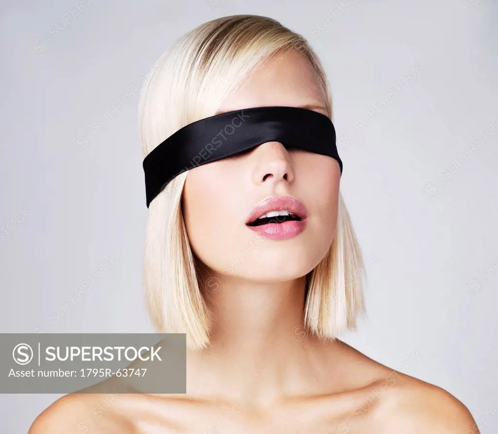 Young woman wearing blindfold, studio shot
