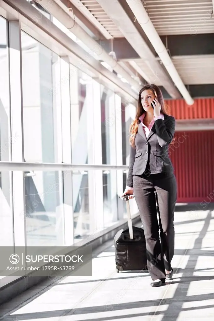 Smiling businesswoman walking with suitcase