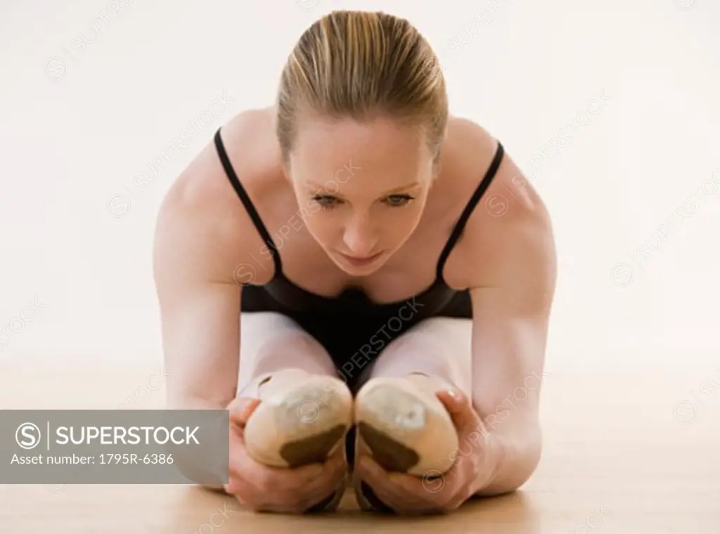 Female ballet dancer stretching on floor