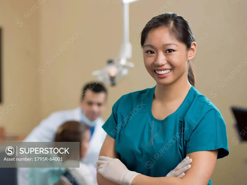 Portrait of dentist, dentist and patient in background