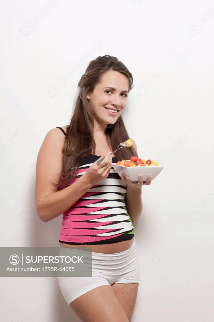 Portrait of pregnant woman holding bowl with salad, studio shot