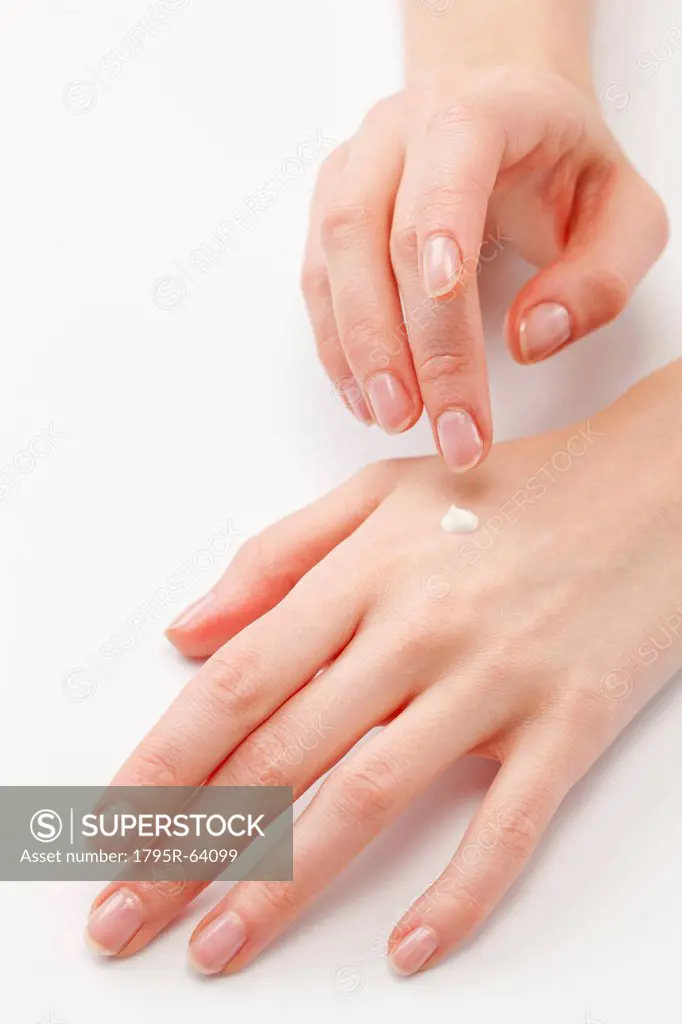 Close up of woman´s hands applying moisturizer, studio shot