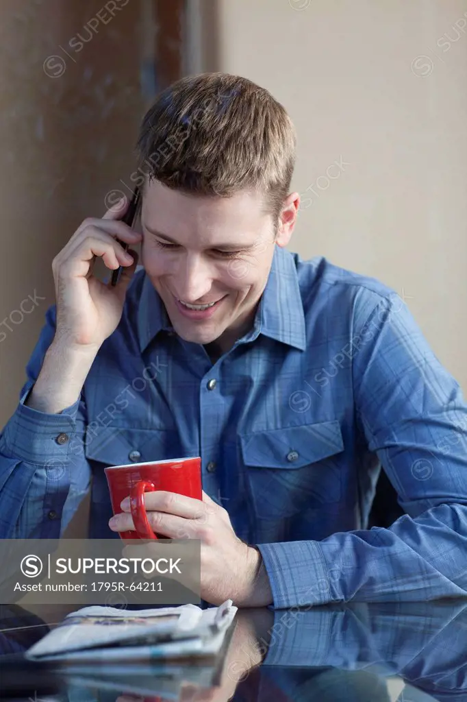 Man drinking coffee and talking on phone