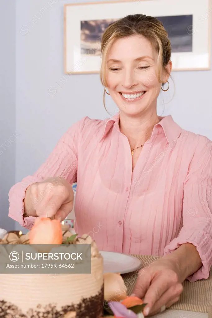 Portrait of mature woman cutting cake