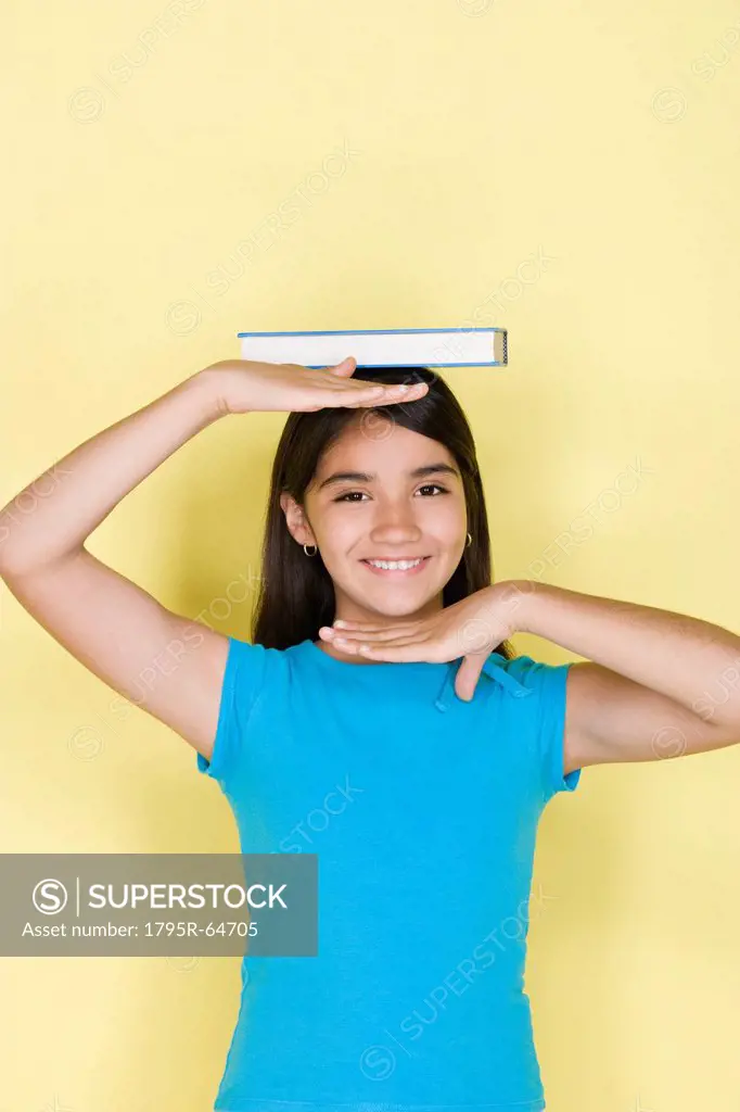 Studio portrait of teenage 16_17 girl balancing book on head