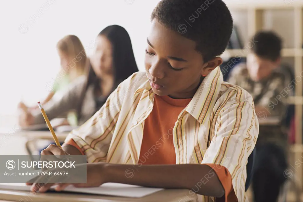 Boy doing notes in classroom