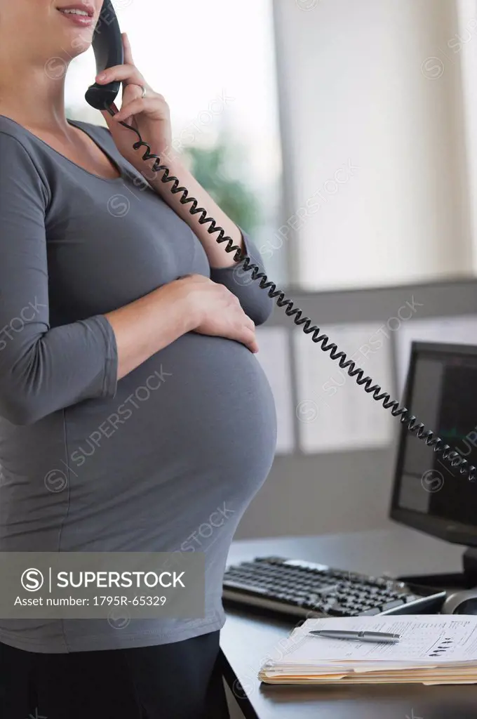 Young pregnant woman working in office