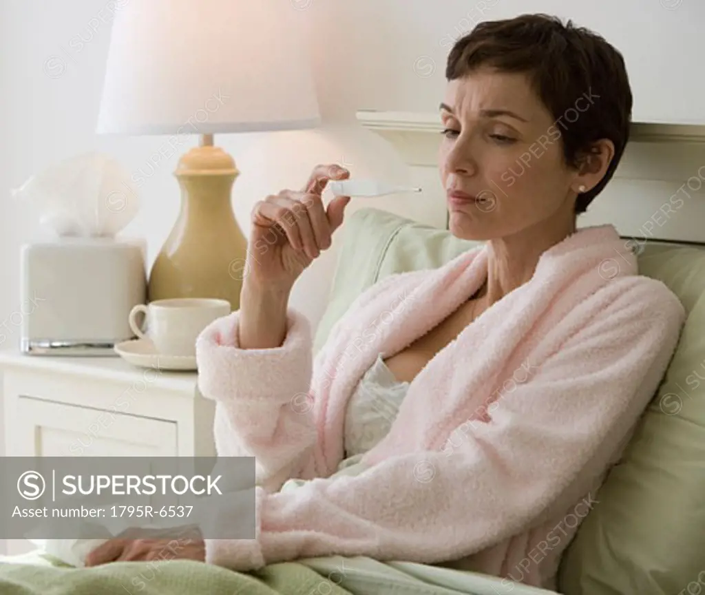 Woman taking own temperature in bed