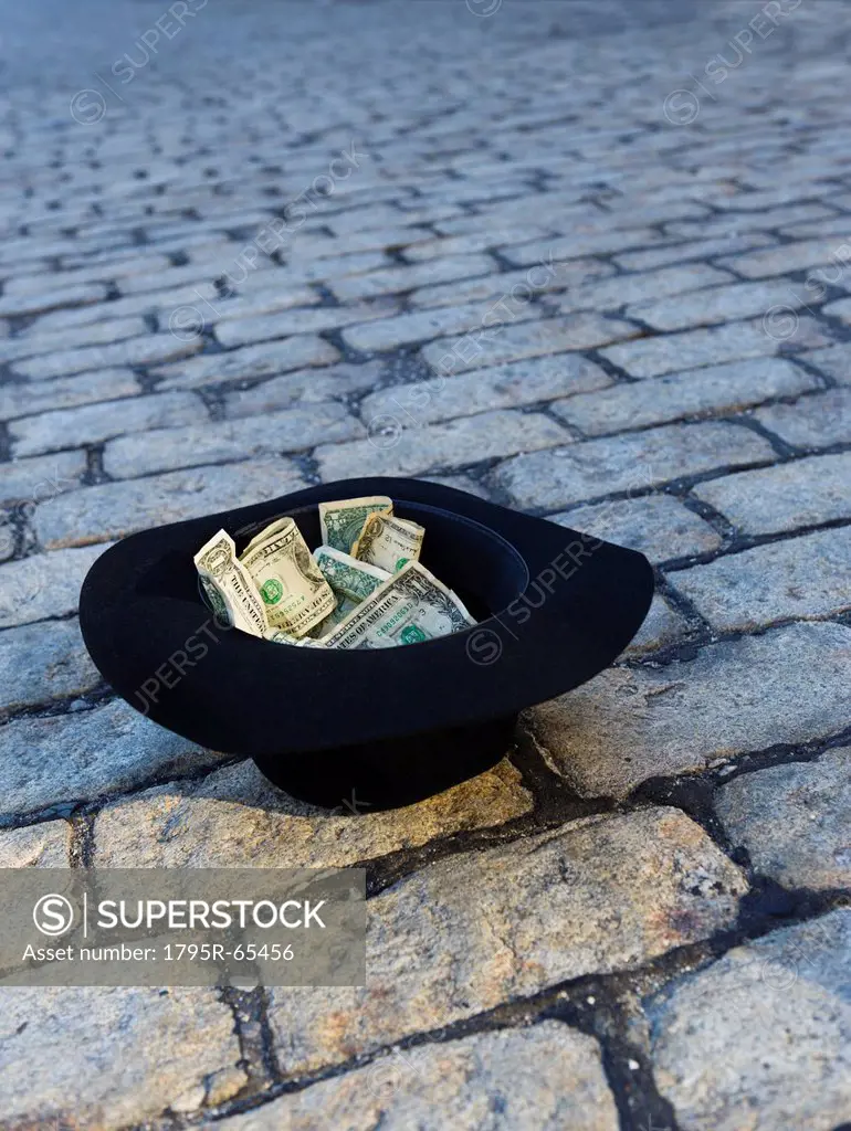 Money in hat on cobblestone street