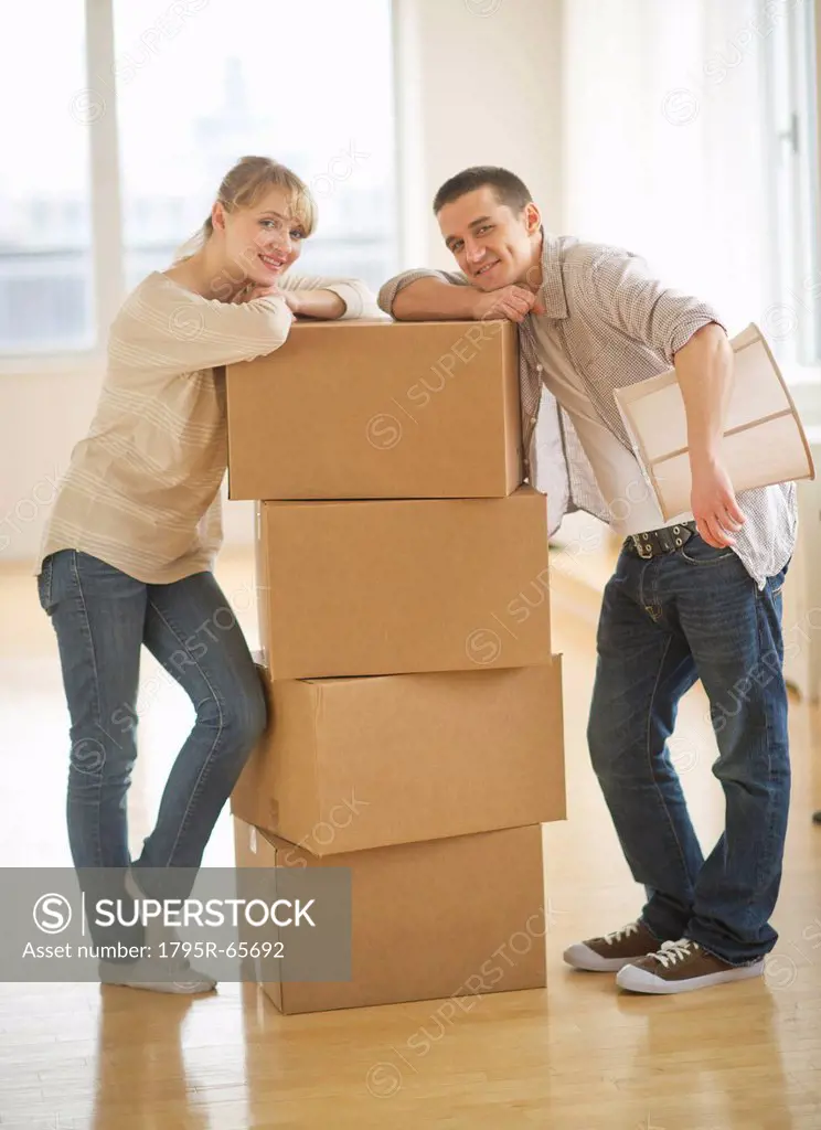 Couple leaning on cardboard boxes during relocation