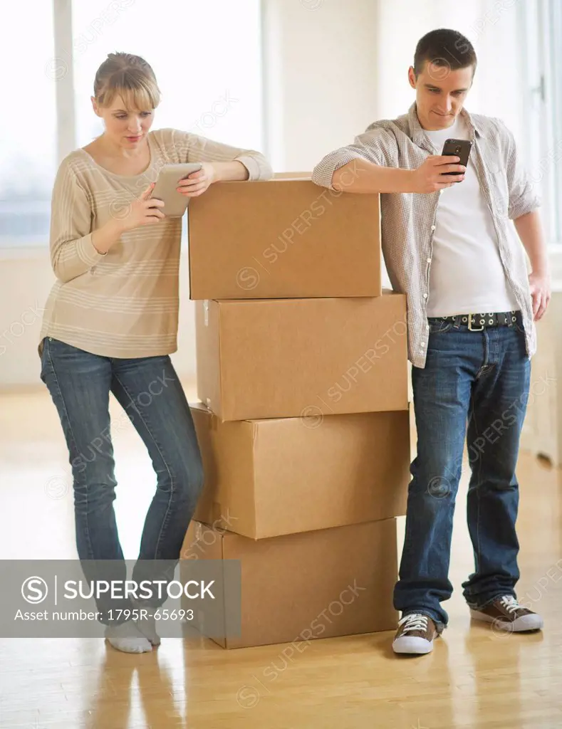 Couple leaning on cardboard boxes during relocation