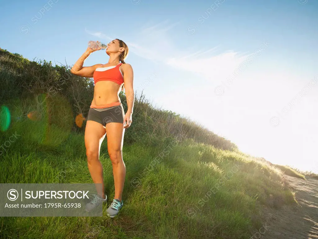 Woman drinking water during training on coast