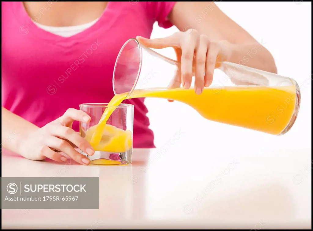 Young woman pouring juice into glass