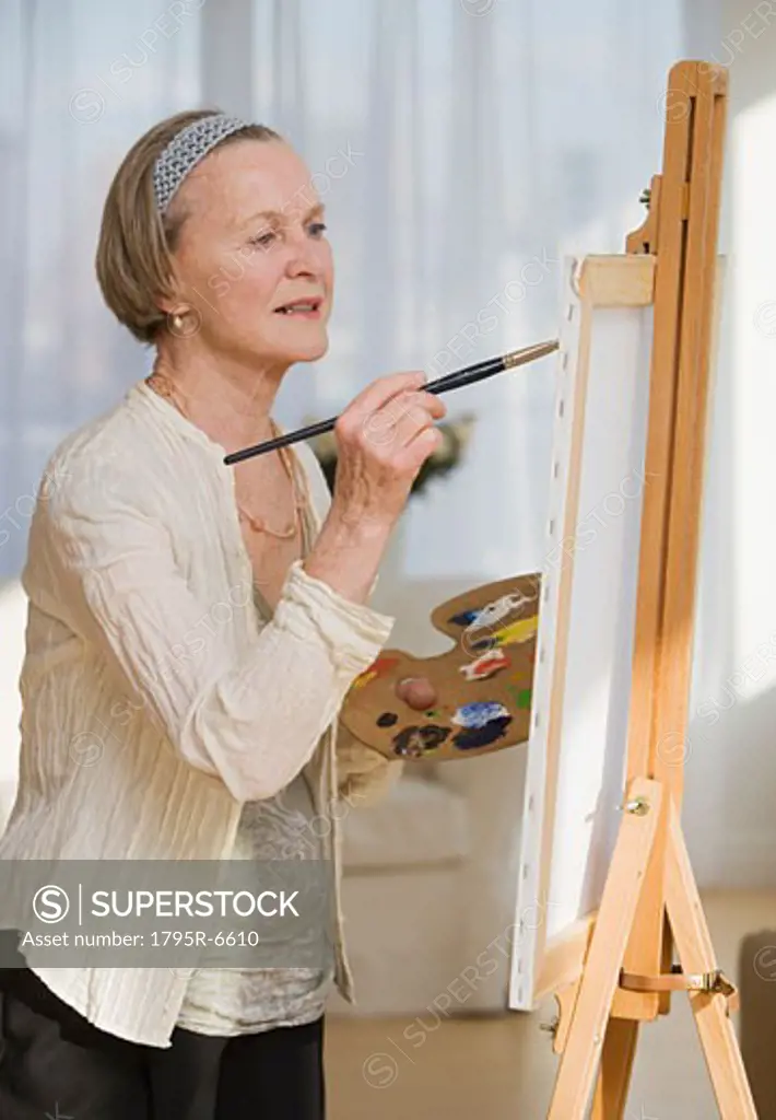 Senior woman painting on easel
