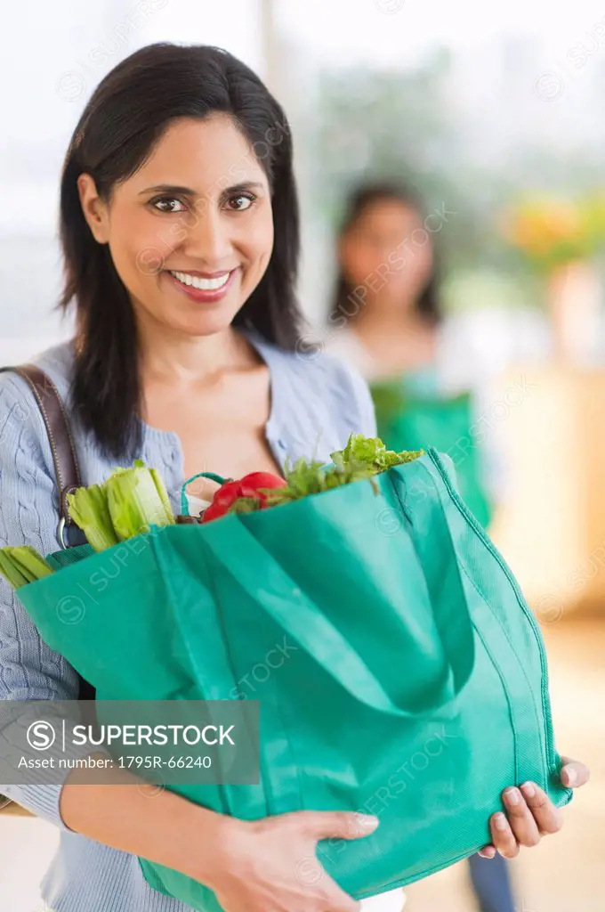 Woman holding bag of fresh vegetables