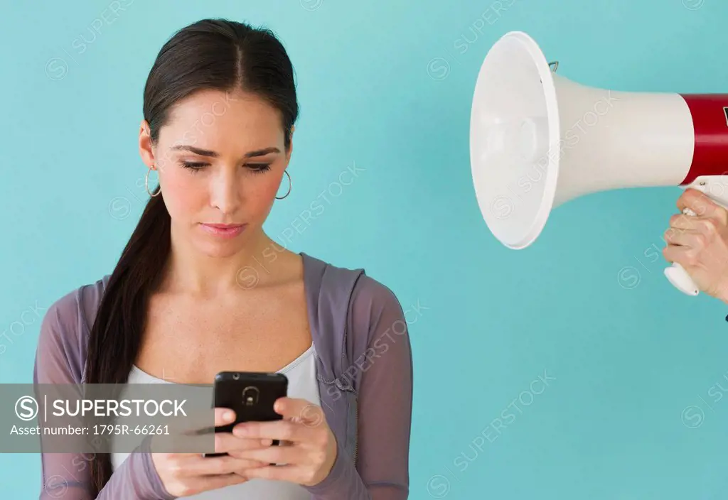 Studio shot of woman texting and ignoring voice from bullhorn