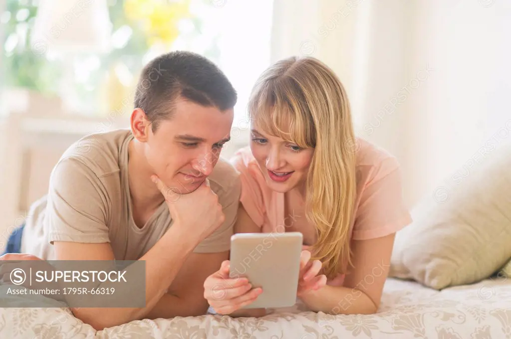 Couple lying on bed and using digital tablet