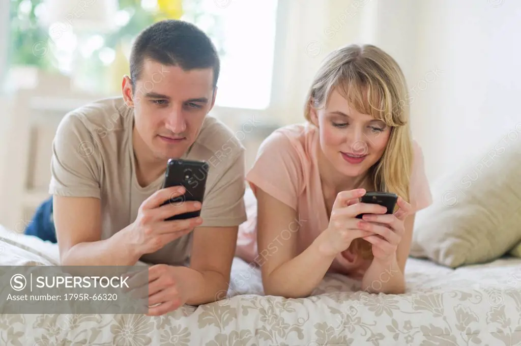 Couple lying on bed and using smart phones
