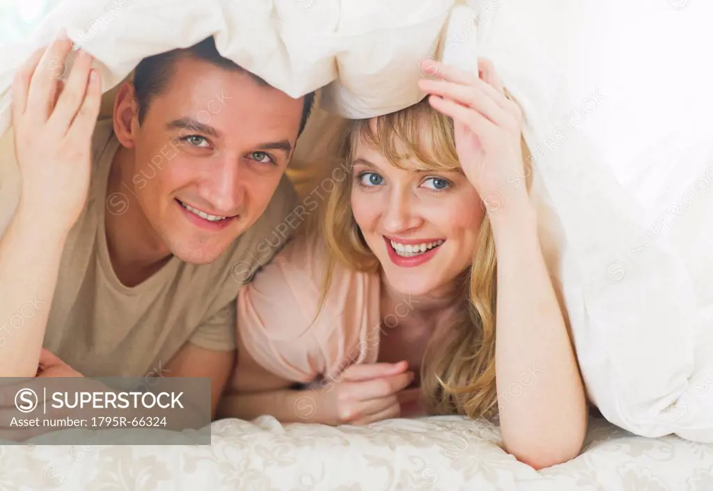 Couple lying on bed under duvet