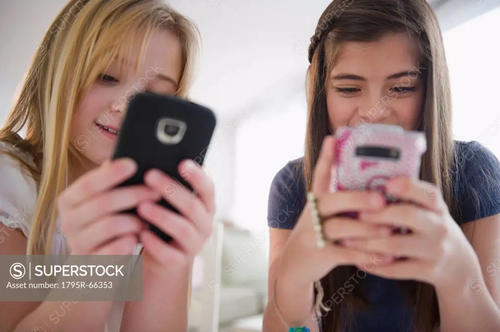 Two girls texting on smart phones