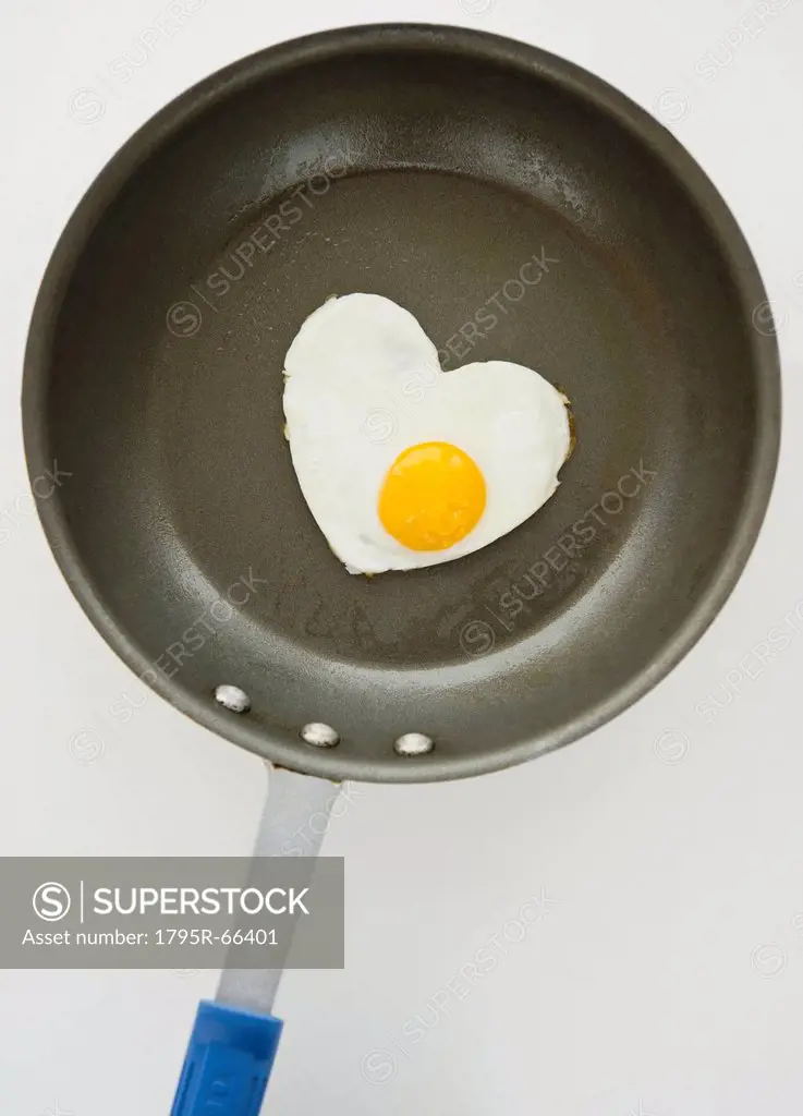 Close up of fried egg in heart shape on frying pan, studio shot