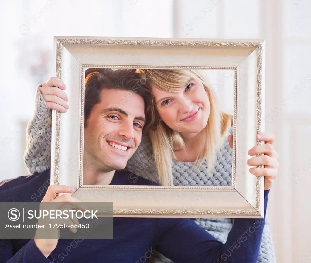 Portrait of smiling couple holding picture frame