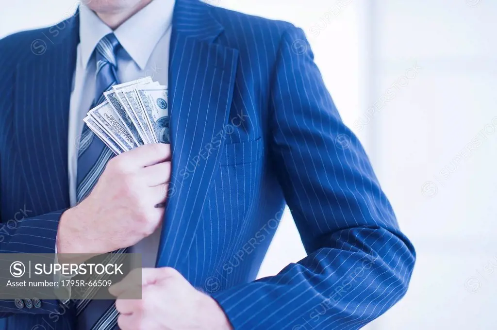 Businessman hiding banknotes in pocket