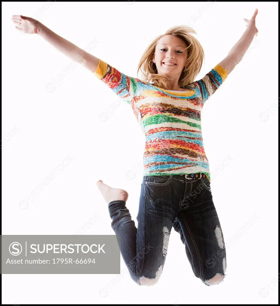 Studio shot of girl 12_13 jumping with arms raised