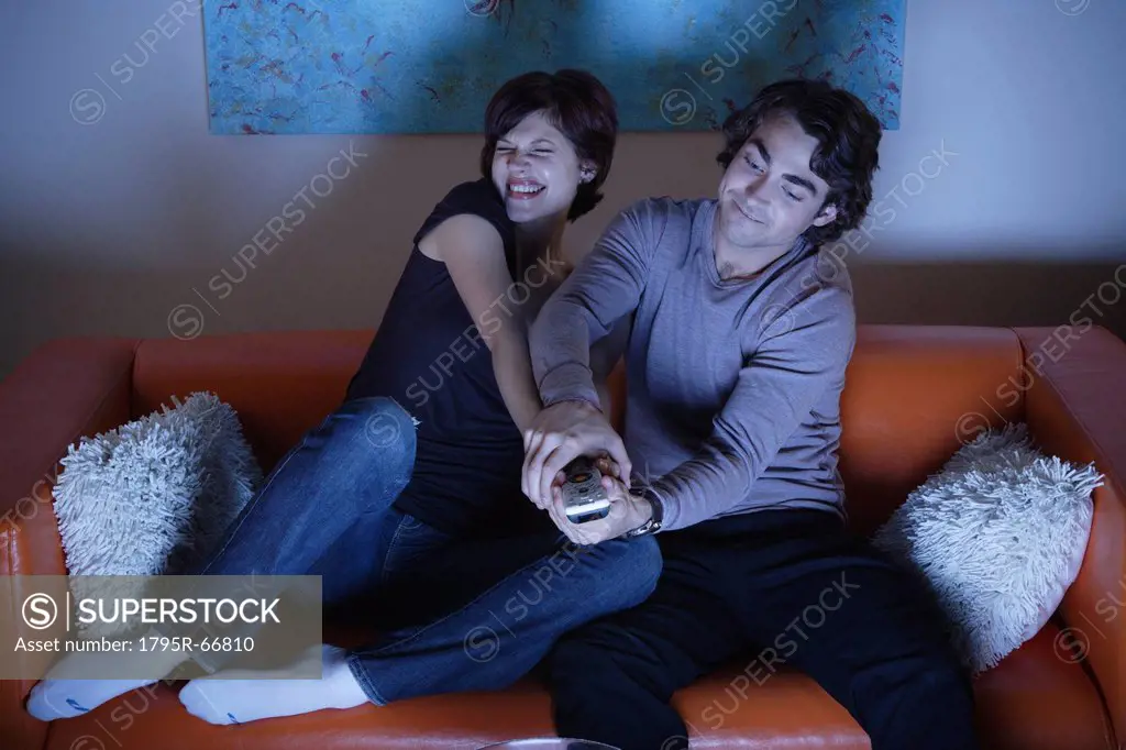 Young couple fighting over TV remote control