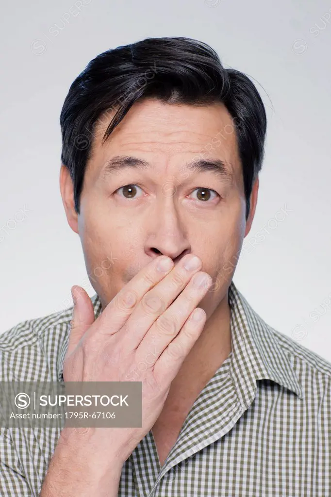 Studio portrait of mature man covering mouth