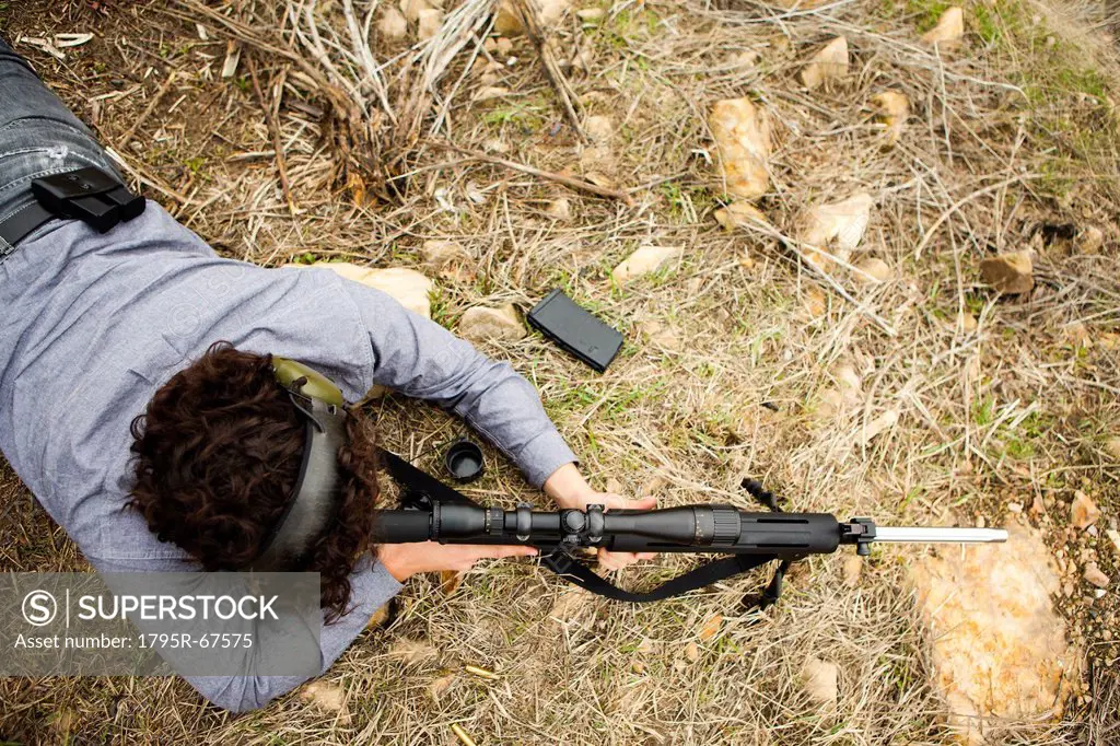 Man lying on front with weapon