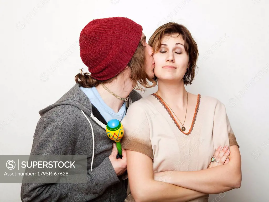 Studio Shot of young man kissing young woman
