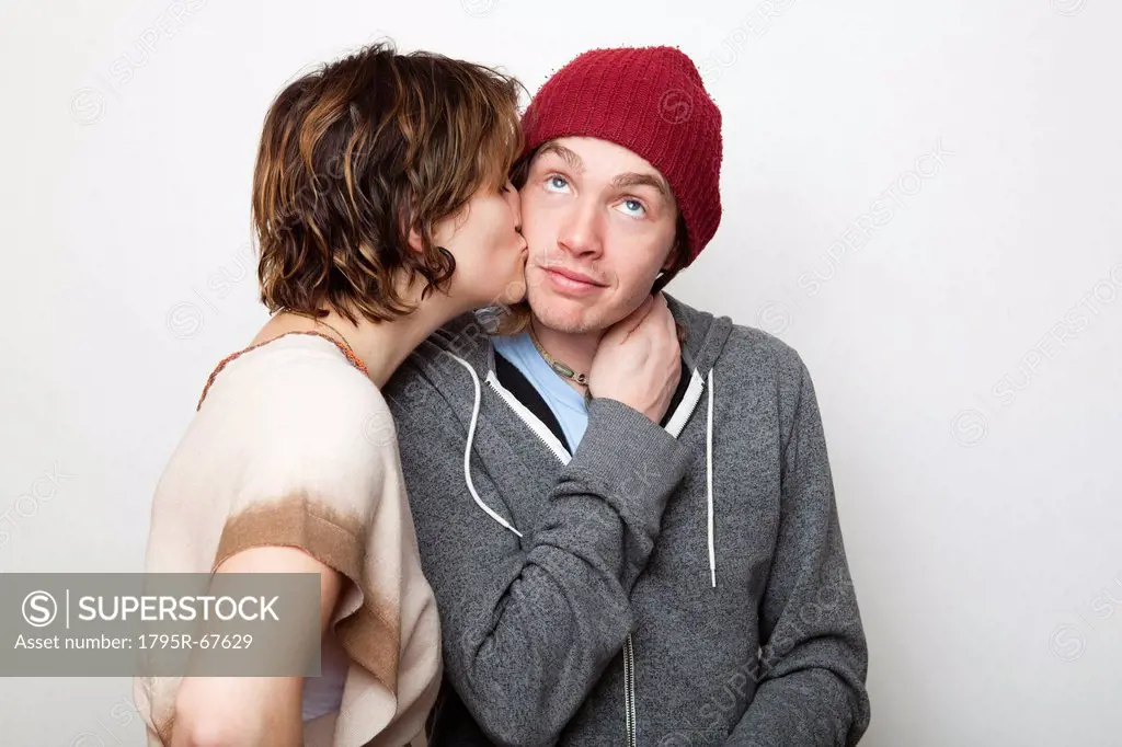 Studio Shot of young woman kissing young man