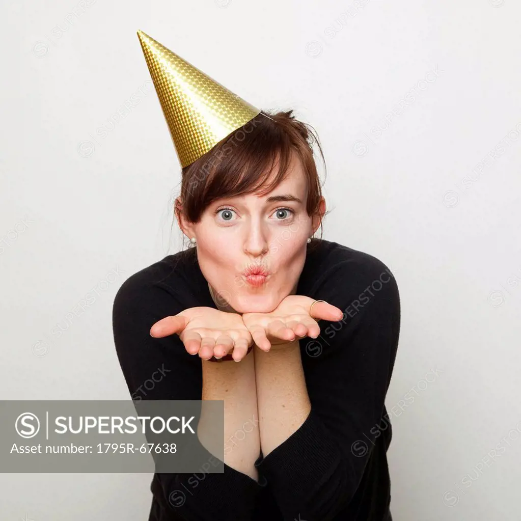 Studio Shot of young woman party hat blowing kiss