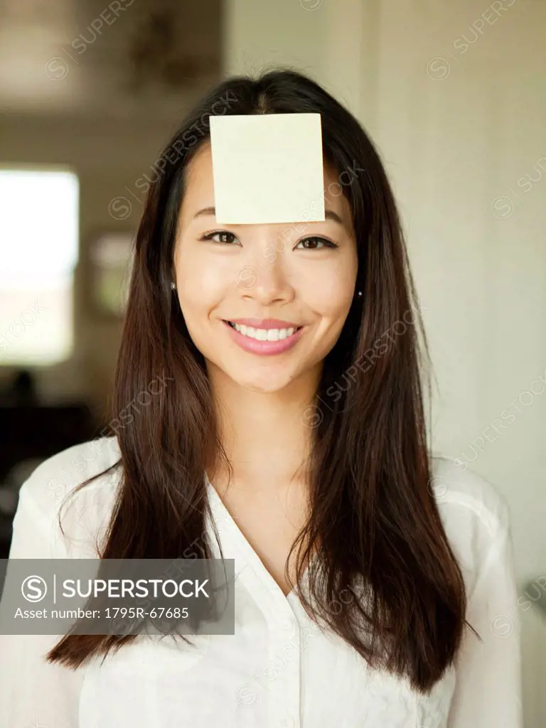 Portrait of young woman with adhesive note stuck to her forehead