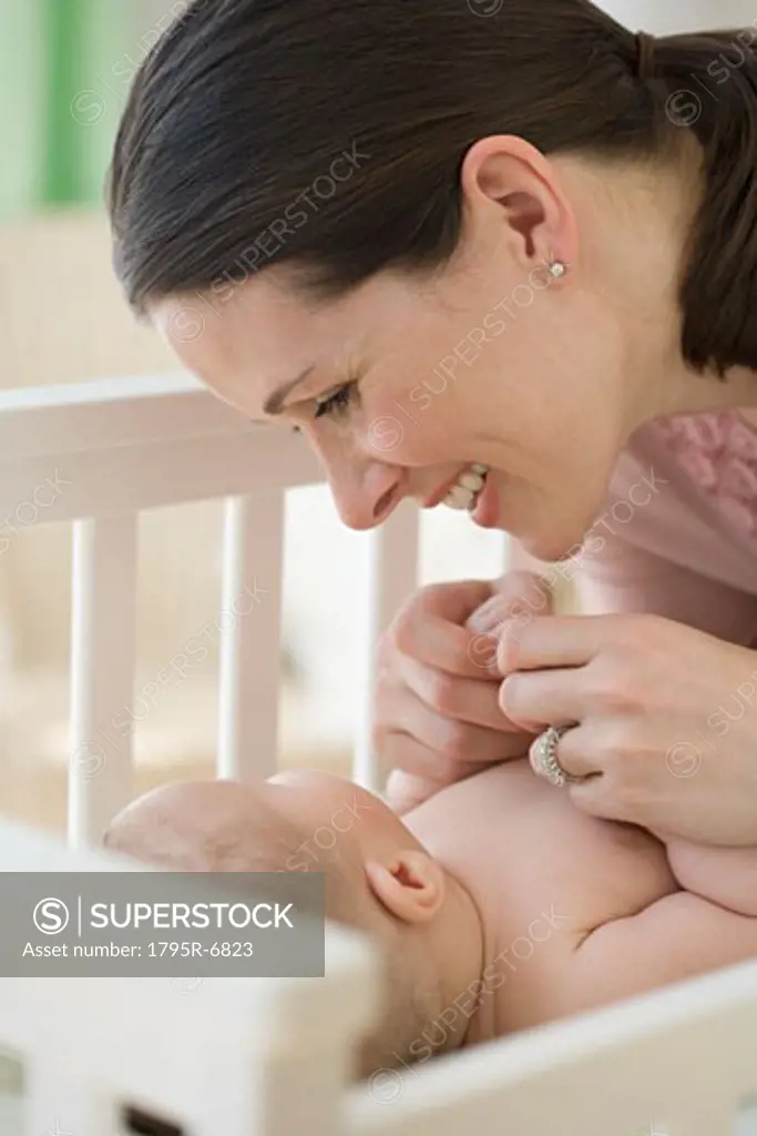 Mother smiling at baby in crib