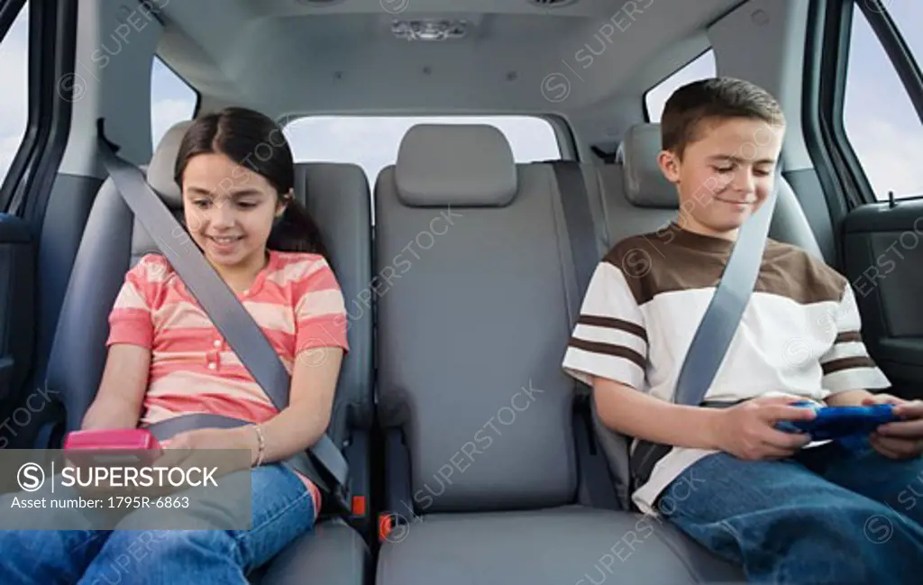 Brother and sister playing video games in car
