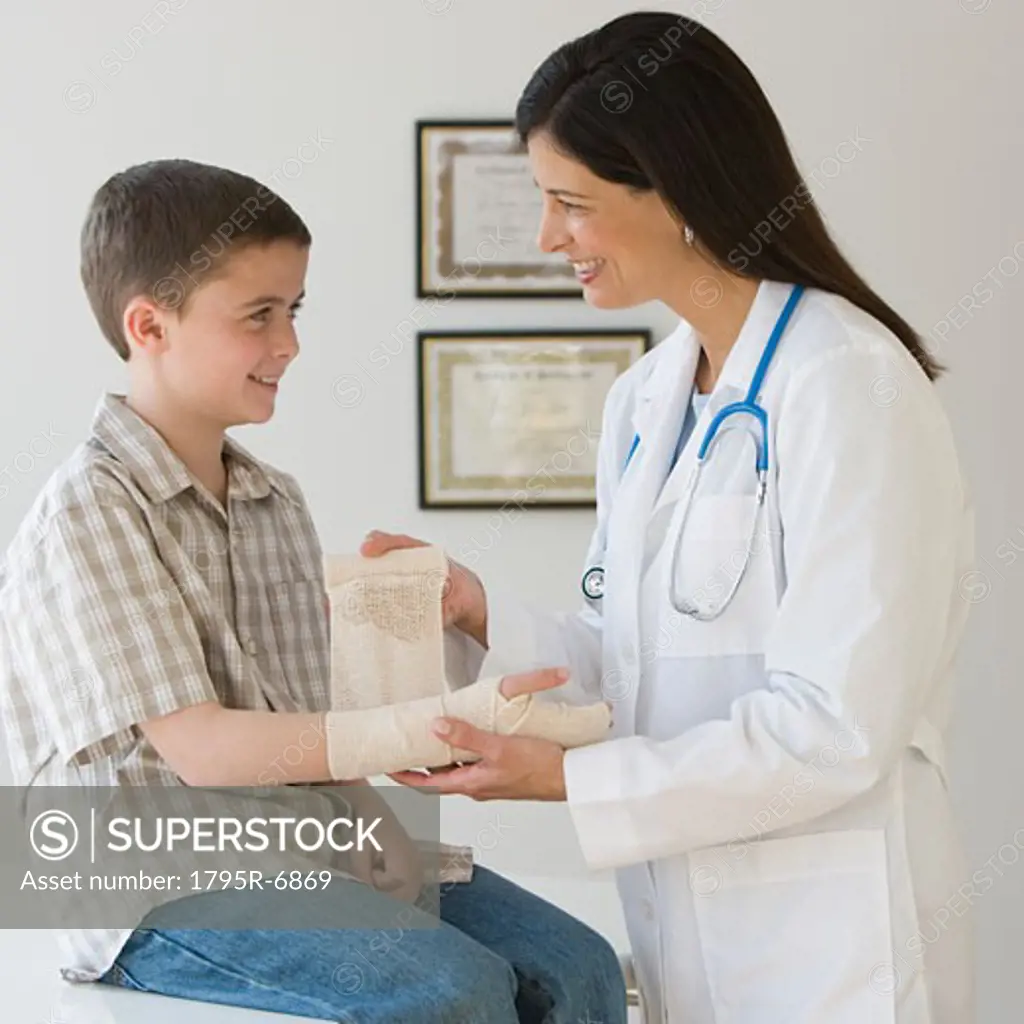 Female doctor wrapping boy's wrist