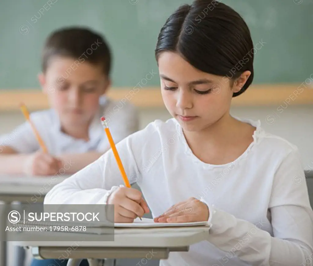 Girl writing at desk in classroom