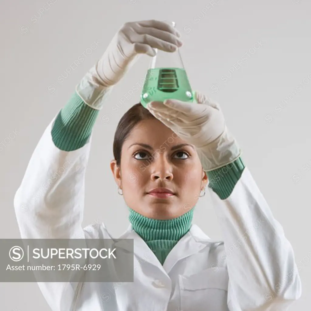 Indian female scientist looking at beaker of liquid