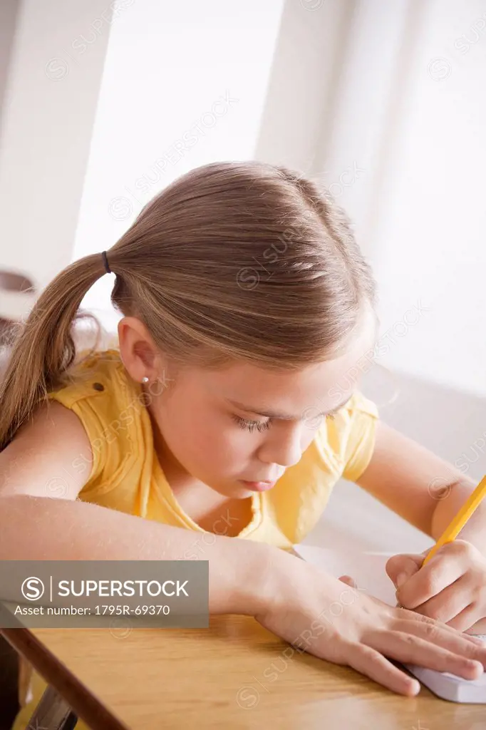 Schoolgirl focused on writing in classroom