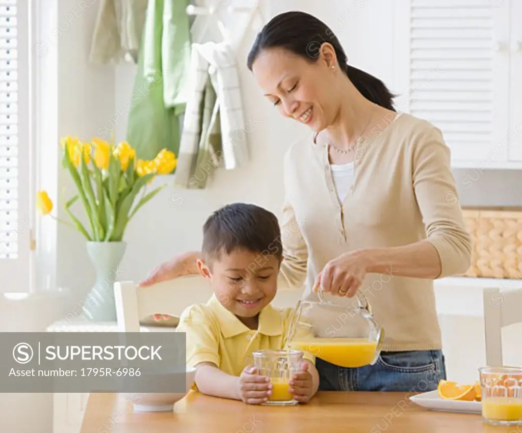 Asian mother pouring juice for son