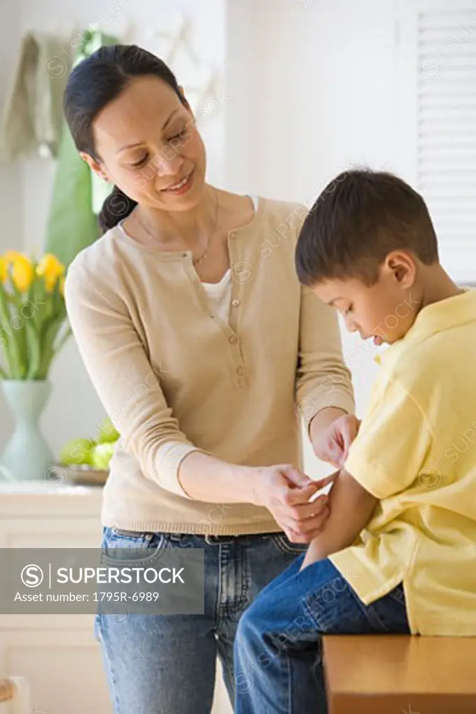 Asian mother putting bandage on son