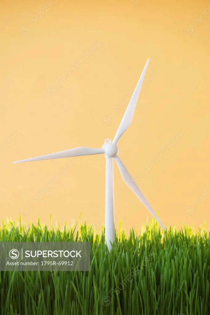Model wind turbines in grass on yellow background