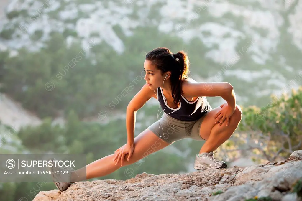 France, Marseille, Young woman stretching on cliff