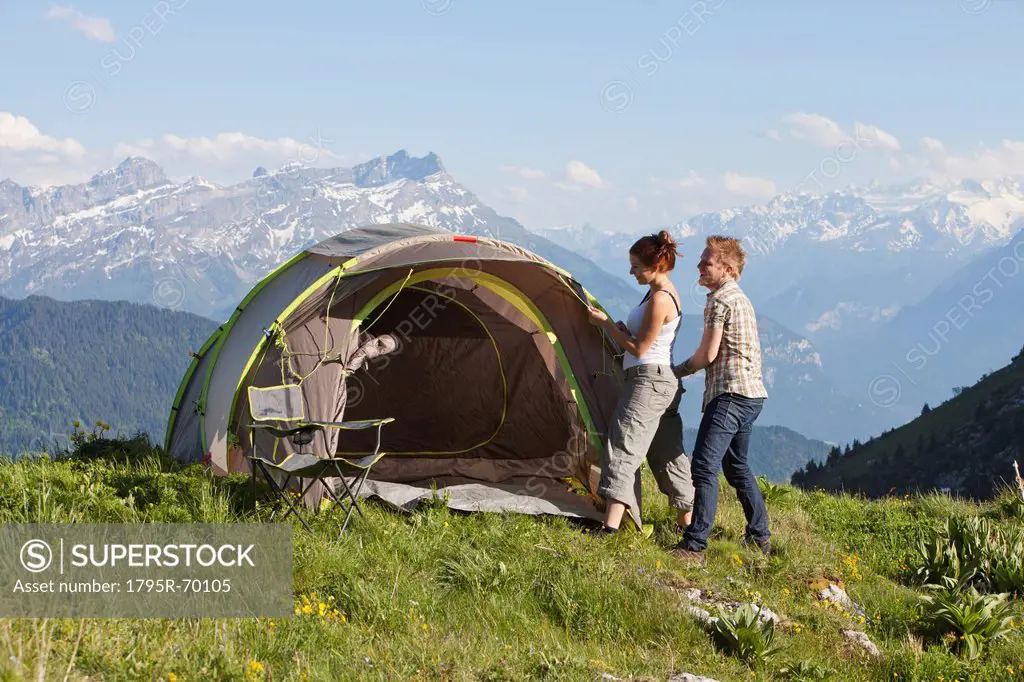 Switzerland, Leysin, Hikers pitching tent on meadow