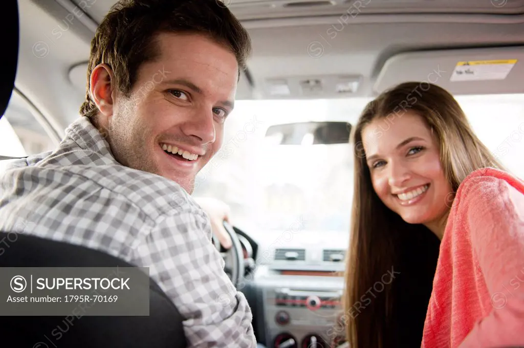 Happy young couple sitting in car