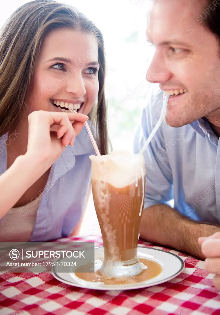 Happy young couple drinking milk shake